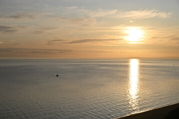 Sun setting over the calm sparkling waters of Port Phillip Bay, with light cloud in the sky, as a...