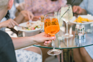 Crop of friends drinking cocktails and eating on cafe terrace on sunny day. Summer lifestyle.