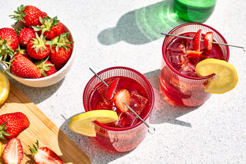 Fresh summer strawberry cocktail or mocktail on the table in the garden. Sparkling pink strawberry lemonade.