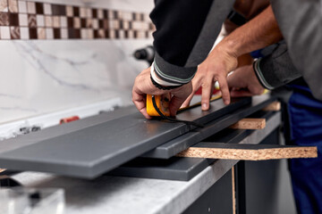Handyman making kitchen wall cabinets in the apartment.
