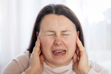 Young woman have headache migraine stress or tinnitus - noise whistling in her ears.