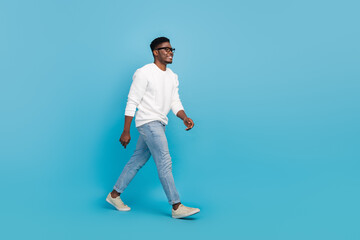 Full size profile portrait of satisfied glad young person walk look empty space isolated on blue color background © deagreez