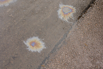 A patch of spilt oil has mixed with rain to show iridescent rainbow colours on a road surface