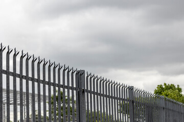 Galvanized steel palisade fence on the border of a property - obrazy, fototapety, plakaty