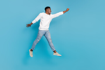 Obraz premium Full size portrait of excited energetic man flight raise arm look empty space isolated on blue color background