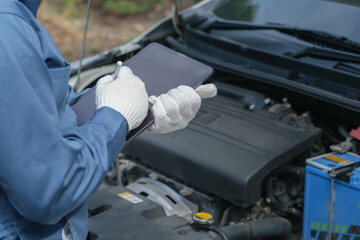 technician mechanic using a tablet computer periodic vehicle inspection Check for breakdowns, maintenance, update information, electric cars, check services