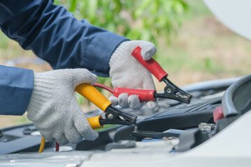 Car service, repair, maintenance concept. Close up of hands  electrician repairs car, tester and engine oil and nippers.call a technician broken car emergency on the way