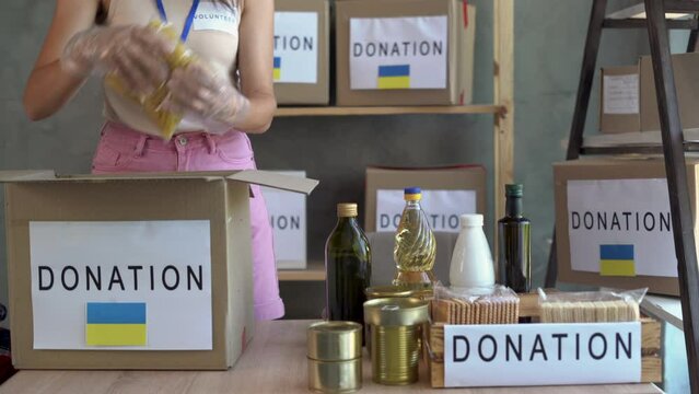 Donation of food for refugees from Ukraine affected by the war, support for the victims, helping people, charity, a box with the Ukrainian flag.