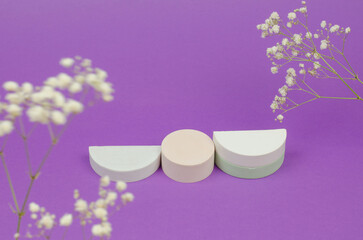 Empty beige podium on purple background with gypsophila flowers. Gypsum podium for the presentation of cosmetic products