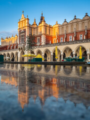Fototapeta na wymiar Reflections of Cloth Hall Sukiennice building at sunrise on main square of Krakow city, Poland