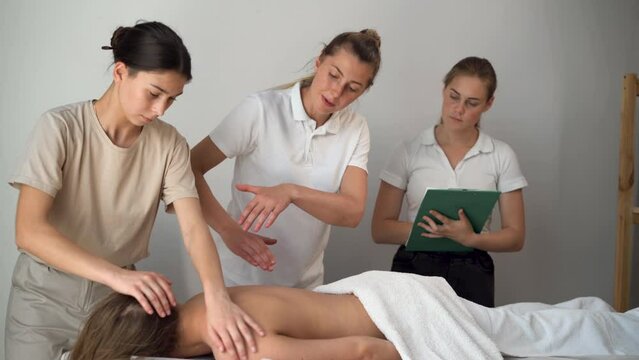 wellness massage training. A group of students studying to be a masseuse, a teacher helping students become masseuses