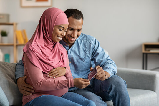 Future Parents. Happy Black Muslim Couple Looking At Baby Sonography Photo