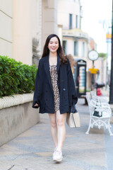 Obraz premium Asian beautiful woman is smiling happily which holds bag in her hand and walking in town.