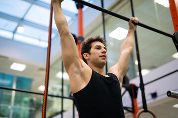 Man doing free body calisthenic pull-ups in a gym