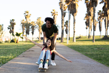 Boyfriend and girlfriend enjoy outside. Happy couple with skateboard having fun
