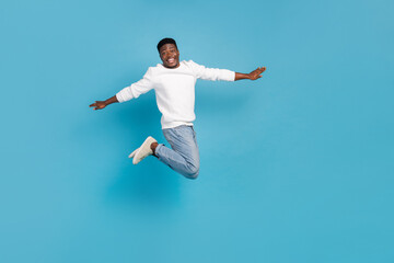 Fototapeta na wymiar Full length portrait of overjoyed energetic person flight raise arms isolated on blue color background