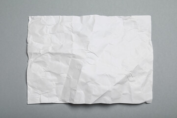 Obraz premium Sheet of white crumpled paper on grey background, top view