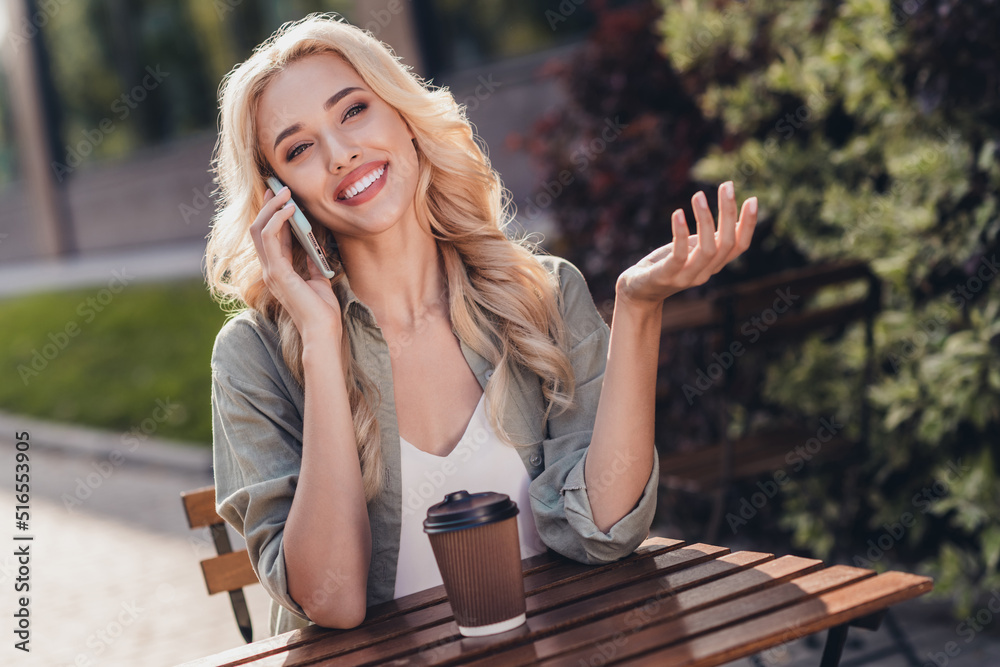 Sticker Portrait of attractive cheerful wavy haired girl talking on phone spending time day drinking coffee latte rest relax outside