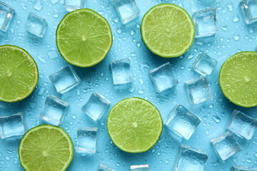 Ice cubes and cut limes on turquoise background, flat lay. Ingredients for refreshing drink