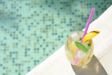 Refreshing drink with citrus slices and mint near swimming pool, above view. Space for text