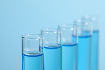 Test tubes with reagents on light blue background, closeup. Laboratory analysis