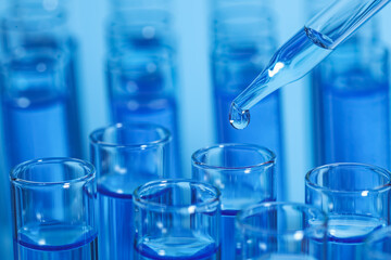 Dripping reagent into test tube on light blue background, closeup and space for text. Laboratory analysis