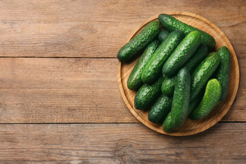 Fresh ripe cucumbers on wooden table, top view. Space for text