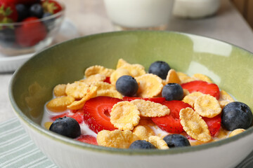 Corn flakes with berries in bowl served on grey table, closeup