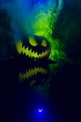 Composition of halloween carved pumpkin with smoke, green and blue light on black background