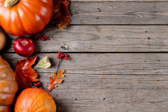 Composition of pumpkins and autumn leaves on wooden background