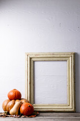 Composition of pumpkins with autumn leaves and frame with copy space on white background