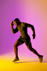 Fototapeta na wymiar African american male runner with sportswear over pink lighting
