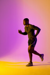 Fototapeta na wymiar African american male runner with sportswear over pink lighting