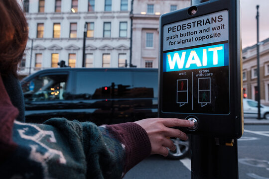 pushing a button of a signal traffic light at pedestrian crossing in London
