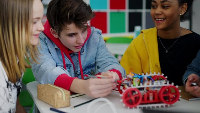 Group of high school students building and programming electric toys and robots at robotics classroom