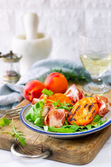 Summer salad with grilled apricots, rocket leaves and Italian pork cold cut coppa