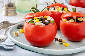 Stuffed red ripe tomatoes with rice and vegetables like zucchini, corn, black olives