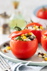 Fresh ripe tomatoes stuffed with rice salad with corn, courgette and black olives