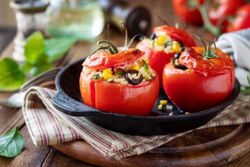 Oven baked stuffed tomatoes with rice and vegetables like zucchini, corn and black olives