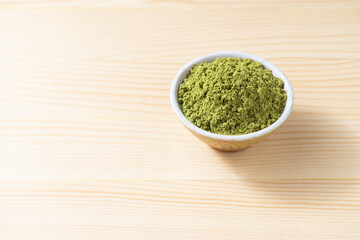 Henna powder in cup on space of pine wood background