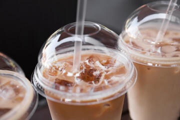 Plastic takeaway cups of delicious iced coffee with straws, closeup