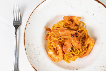 Pasta spaghetti with shrimps and tomato sauce served on plate on white background. Seafood menu