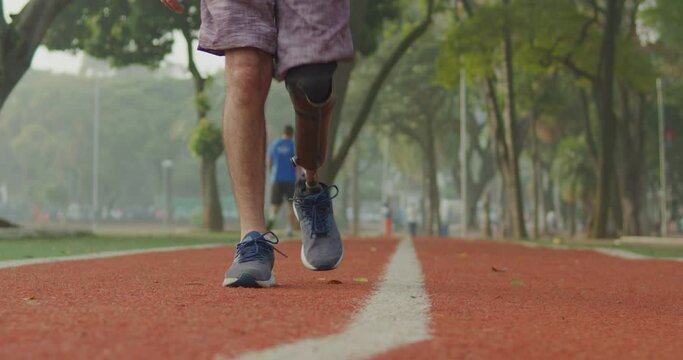Disabled Athlete walking forward with prosthetic leg at running track