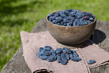 Honeysuckle in a wooden bowl on an old wooden table on a sunny day