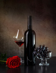 Wine, grapes and red rose on a dark background