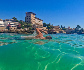 Beautiful scene of a man swimming crawl sltyle in a blue crystal clear watter beach. Concept of...