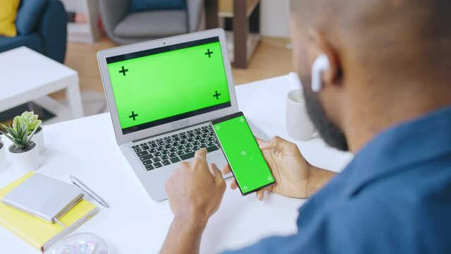 Black man using smartphone and laptop to order services online, pre-keyed screen