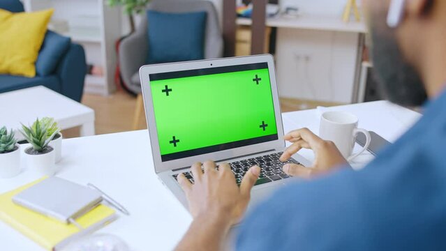 African American man looking at pre-keyed laptop screen, typing on keyboard