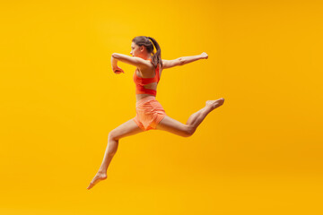 Full-length portrait of young sportive girl in motion isolated on bright yellow background. Modern sport, action, motion, summer, vacation, youth concept.
