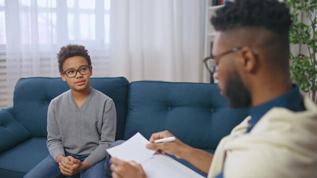 African American male school psychologist talking with a boy, child therapy